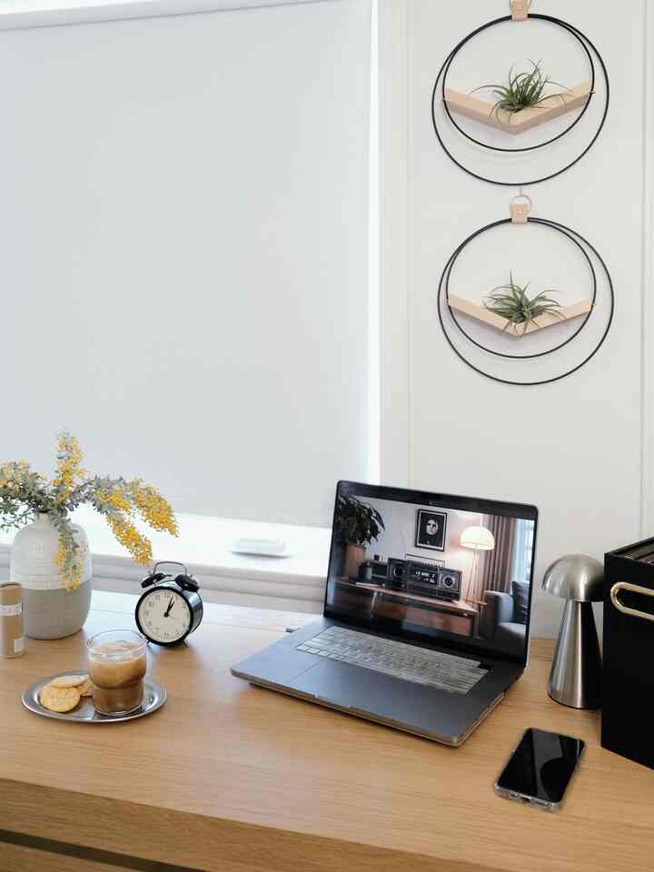 Wood-toned home office space featuring a simple desk with a laptop, alarm clock, and iced coffee creating a cozy atmosphere