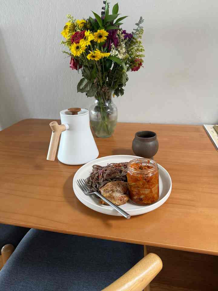 Natural wood tone dining room featuring a vase of flowers and tableware set on the dining table creating a cozy atmosphere