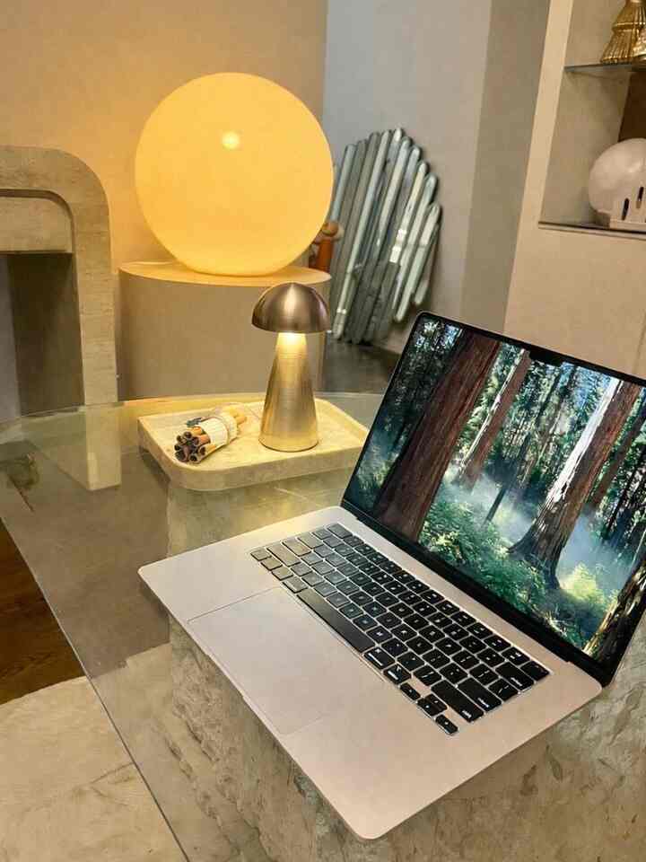 A home office space with warm soft lighting featuring a glass desk and mid-century modern table lamp creating a calm ambiance