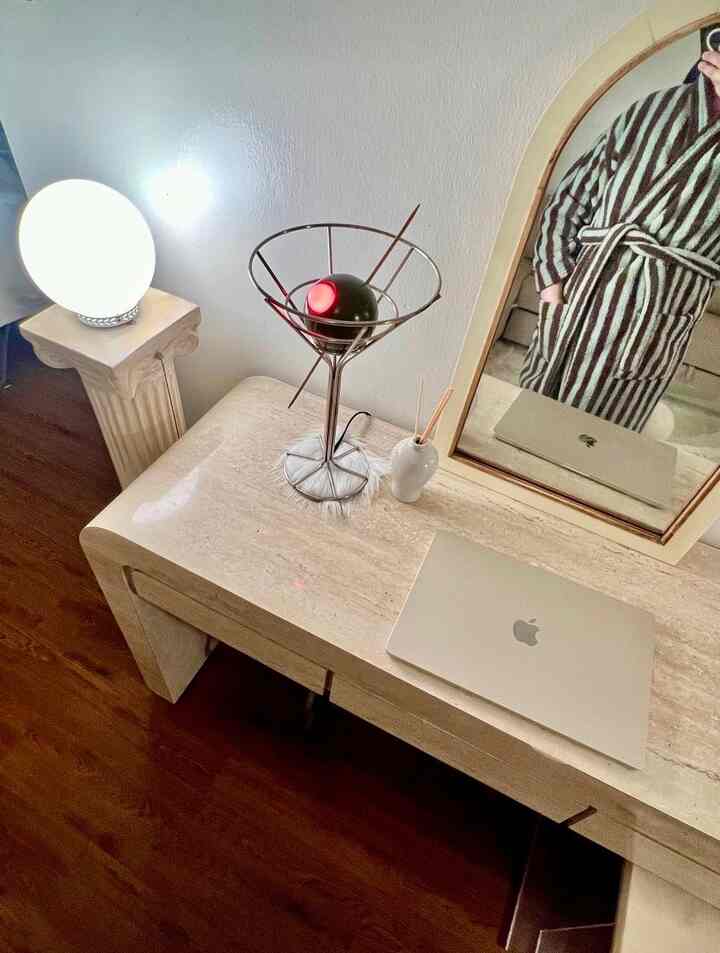 Ivory-toned living room desk space featuring a laptop, table lamp, and mirror, creating a cozy home office atmosphere