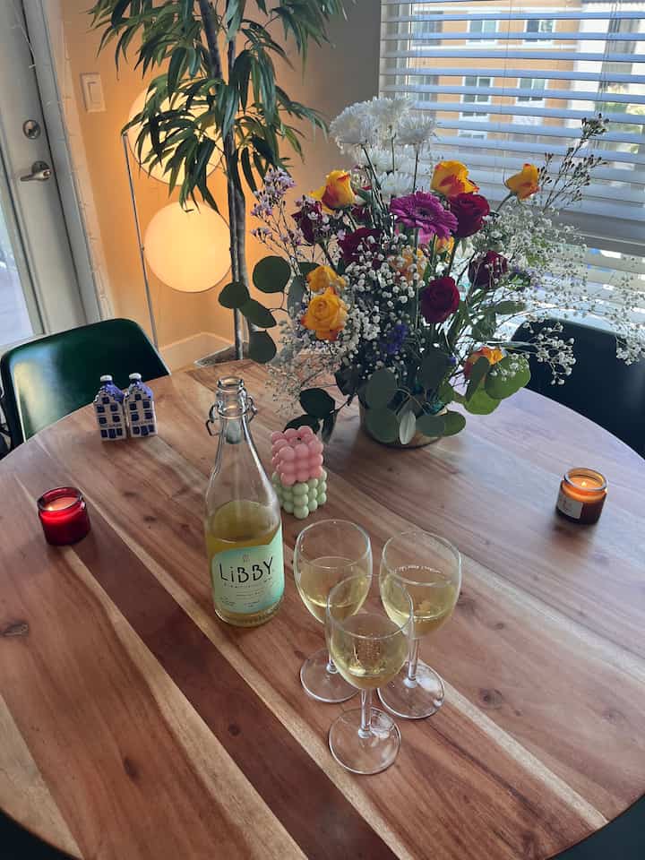 Natural and white toned dining room featuring a wooden dining table with a floral vase and candles creating a cozy tablescape