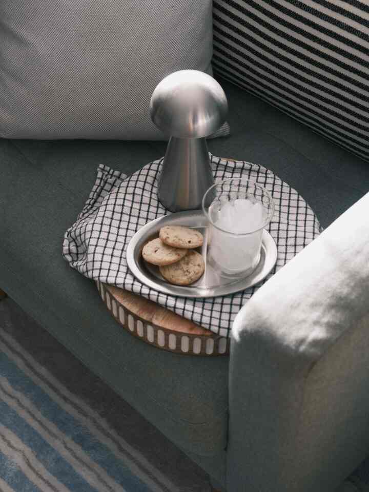 A cozy living room sofa scene featuring stainless steel plate and chrome objet with a transparent glass on gray tones