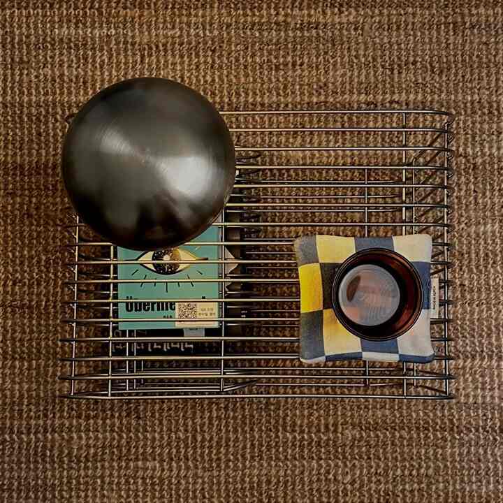 Natural tone space featuring a silver metallic wire table and beige rug with decorative items