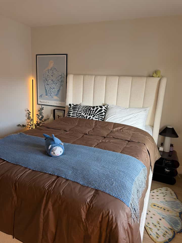 Ivory upholstered bed with brown bedding in a bedroom, featuring a simple and natural atmosphere