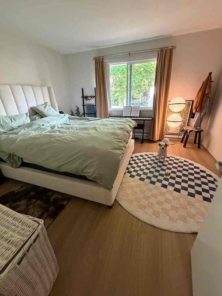 Natural wood tones and beige curtains enhance a two-person bedroom featuring a large central bed and floor lamp, creating a cozy atmosphere