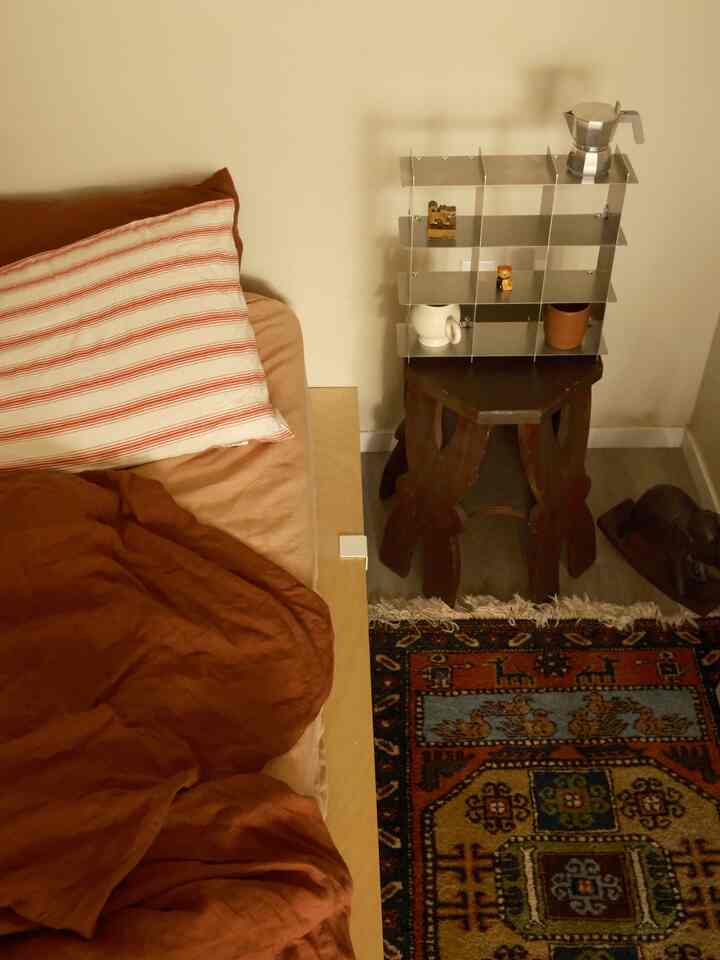 Brown and silver tone bedroom featuring a brown bed frame and chrome metal shelf in a cozy natural space