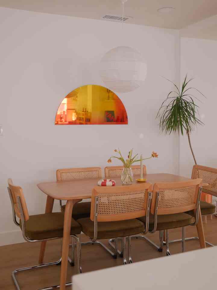 Natural modern dining room with white walls and wood-toned dining table, featuring pendant light and plant creating cozy atmosphere
