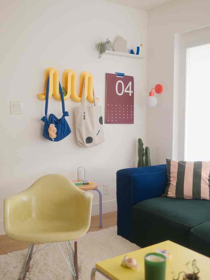 Cozy living room corner with white walls, wood flooring, yellow armchair, and blue sofa