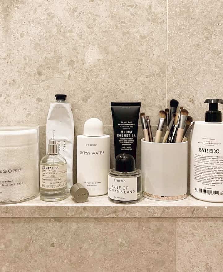 Beige and white toned bathroom featuring neatly arranged cosmetics and makeup brushes in a minimal beauty corner