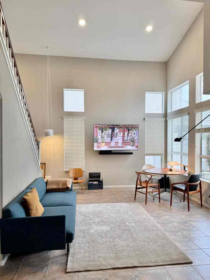 Beige tone walls and carpet, blue sofa and wood tone furniture arranged in a mid-century modern style living room
