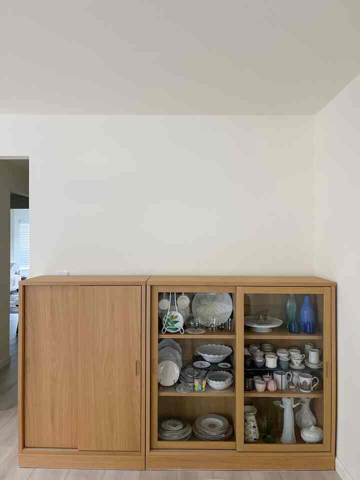 White-walled space featuring a wood-tone storage cabinet neatly displaying various tableware for an organized feel