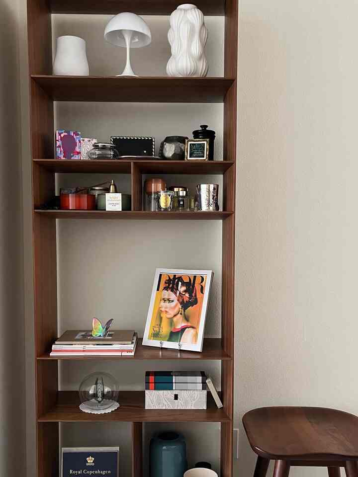 Natural modern interior space featuring brown wood tone shelves against a white wall background with cozy decorative styling