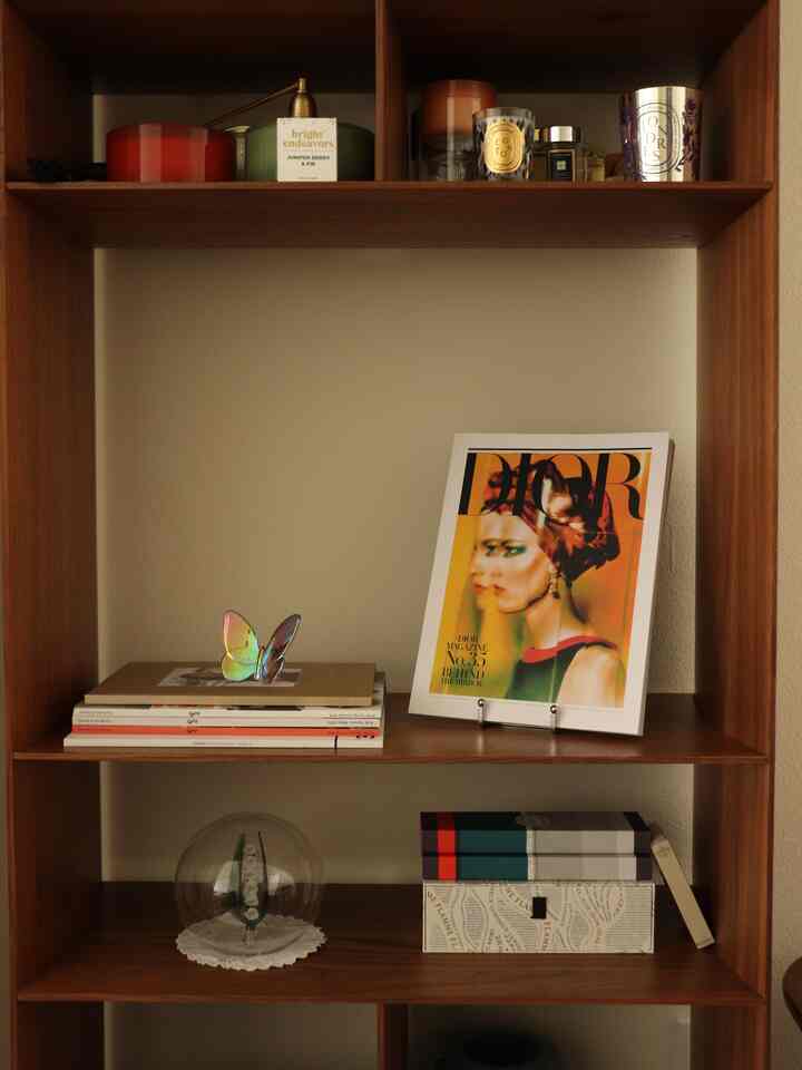 Natural wood-tone shelf featuring spring flowers and decorative objets with a transparent butterfly ornament in warm ambiance