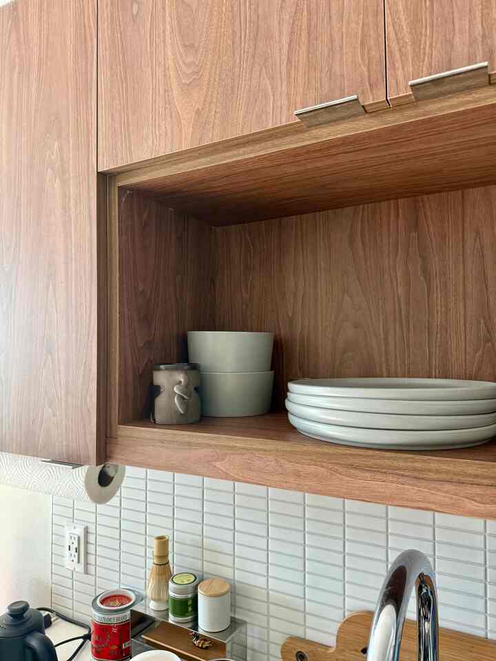 Natural wood tone kitchen space with neatly arranged plates and bowls on open shelves, showcasing clean and warm interior