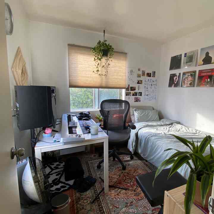 Bright white and warm brown toned compact single household home office with bed and music setup