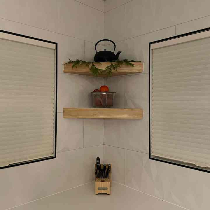 Natural tone kitchen corner featuring wooden shelves and knife block with minimalist, tidy atmosphere