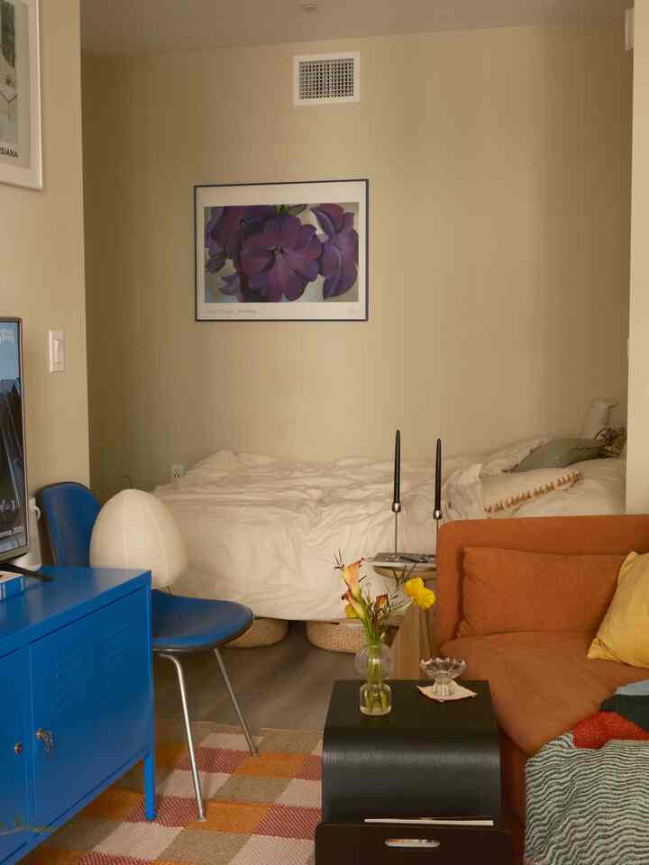 Beige-toned bedroom featuring blue furniture and an orange sofa in a single household space