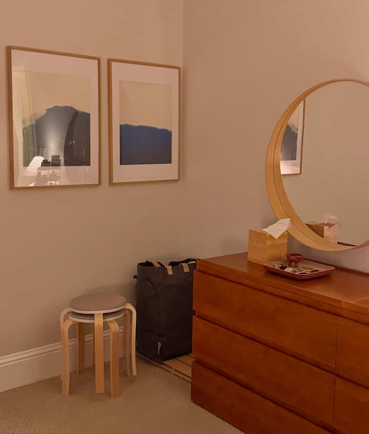 Beige-toned walls and natural wood-tone furniture arranged in a cozy bedroom corner space