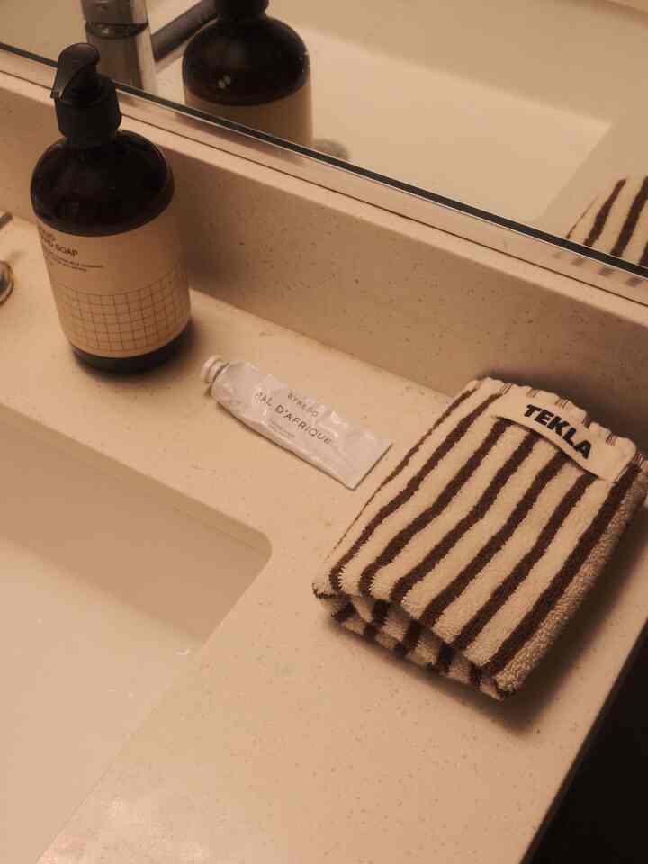 Natural beige-toned bathroom sink area featuring hand soap dispenser and striped hand towel with a clean, cozy atmosphere