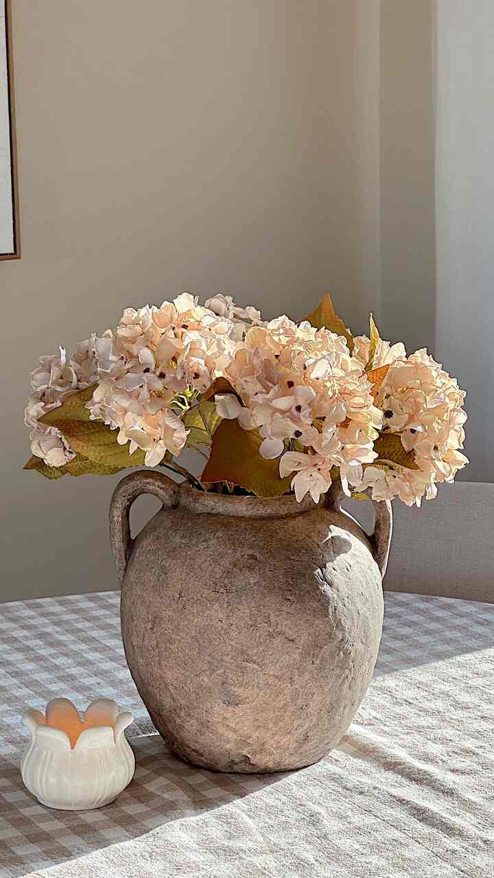Beige-toned dining room featuring a vintage vase with spring flowers under natural light, creating a warm atmosphere