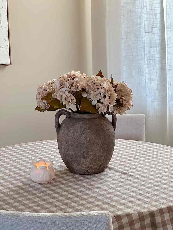 Beige and white toned dining room featuring a vintage-style vase and checkered tablecloth, creating a warm and cozy atmosphere