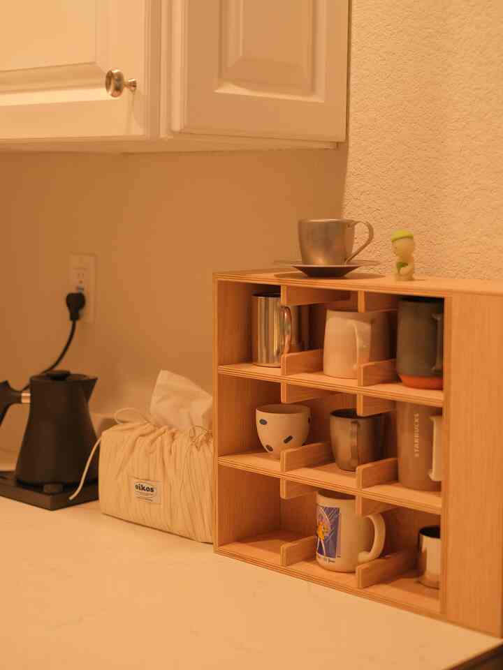 Natural wood tone and white kitchen featuring a Stagg pour-over kettle and organized mug rack creating a clean home cafe environment