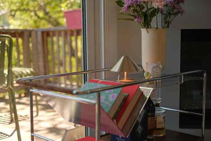 Silver metal bar cart with table lamp, vase, candle styled in a living room bar corner